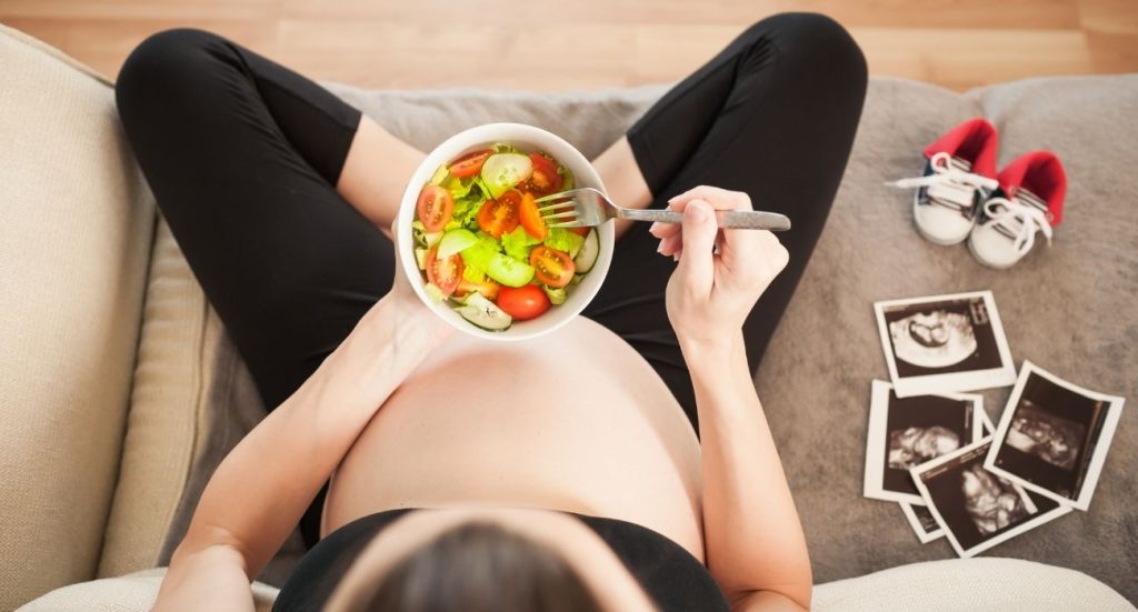 Mulher grávida comendo legumes orgânicos